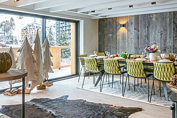 A dining room with green chairs and a sliding glass door