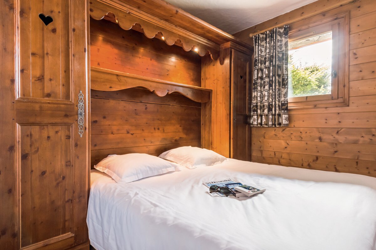 A bed in a wooden room with a magazine on it