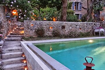 A stone wall surrounds a large swimming pool