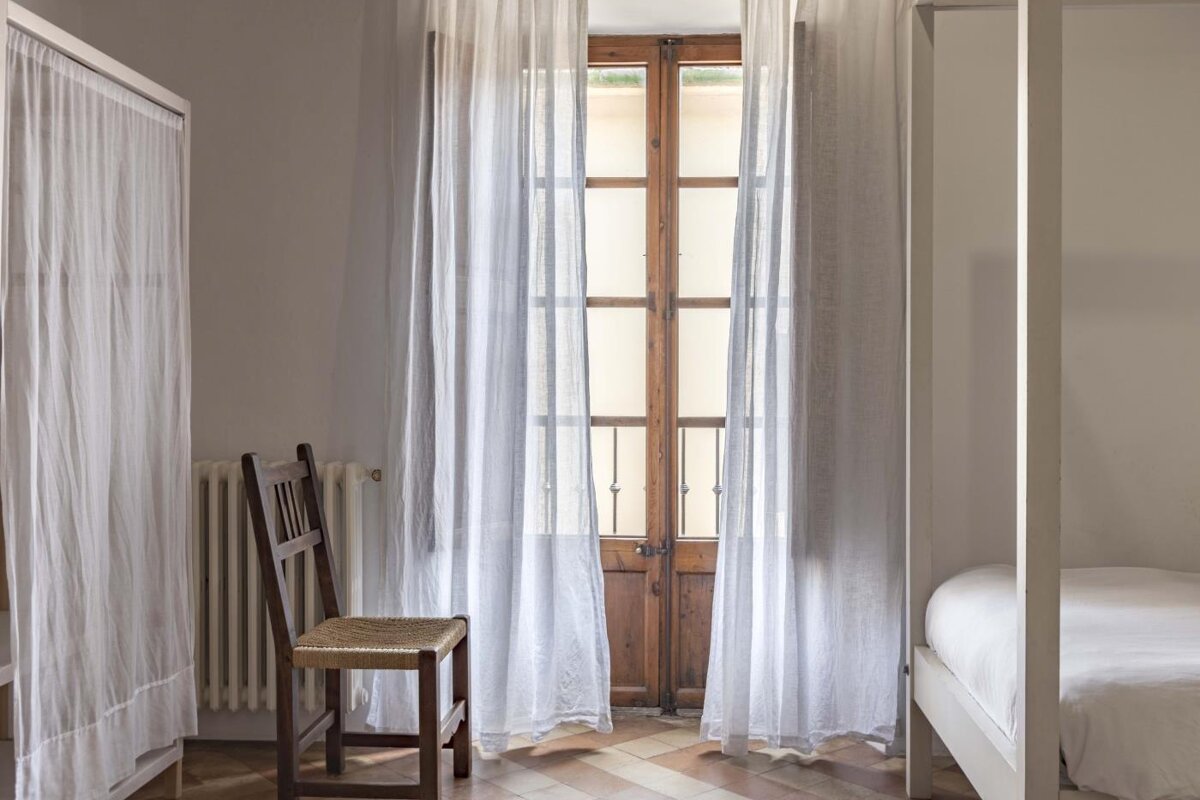 A chair sits in front of a window with white curtains