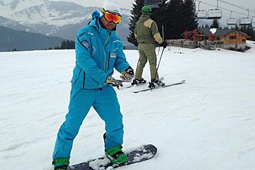a snowboard instructor in blue teaching someone moves