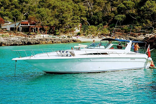 A white boat is floating in the water near a beach