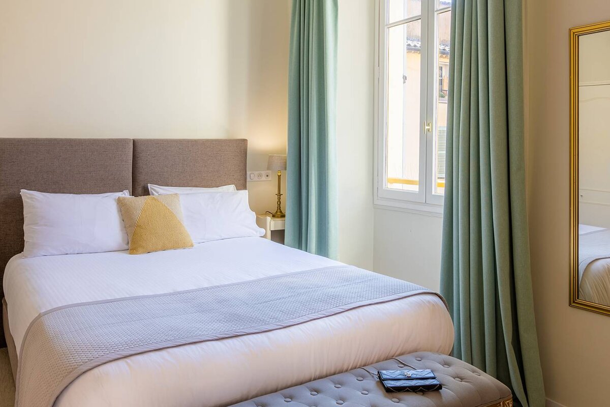 A small bedroom with a bed and a mirror