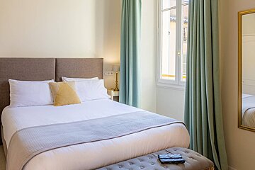 A small bedroom with a bed and a mirror