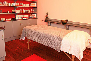 A massage table in a room with shelves full of beauty products