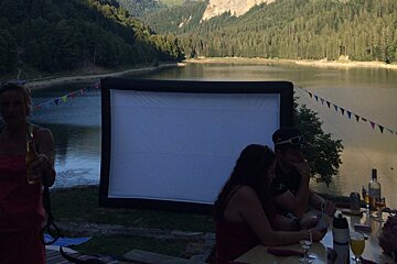 A group of people sitting around a table with a large screen in the background