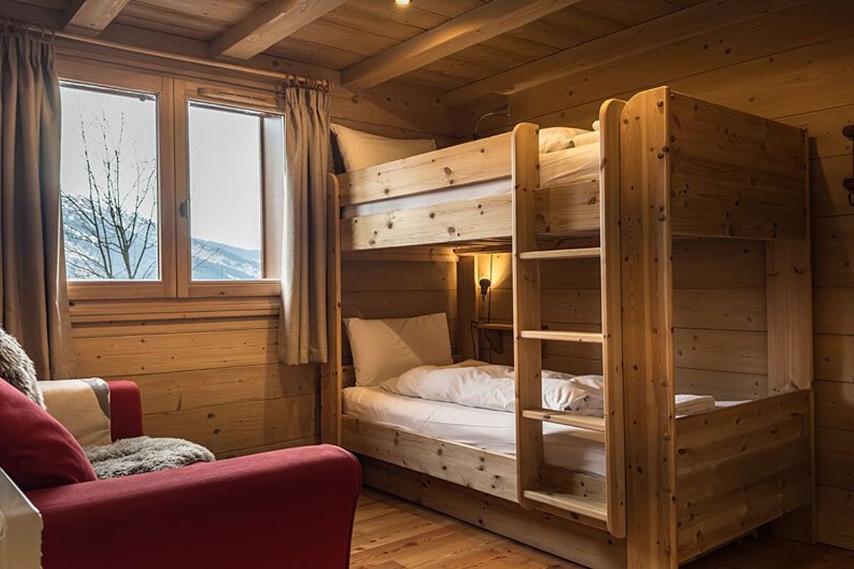 A wooden bunk bed in a room with a red couch