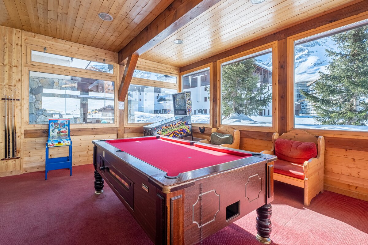 A pool table in a room with a pinball machine