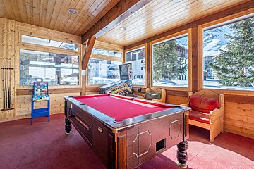 A pool table in a room with a pinball machine