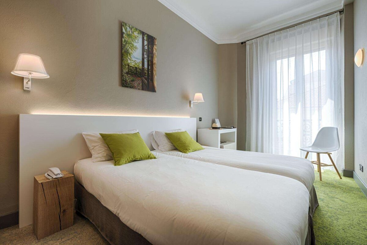 A hotel room with two beds and a picture on the wall