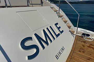 The back of a boat that says smile bikini on it