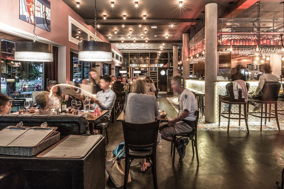 People sitting at tables in a restaurant with a menu on the counter