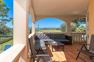A patio with a couch and chairs and mountains in the background