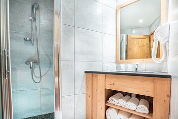 A bathroom with a wooden vanity and a shower