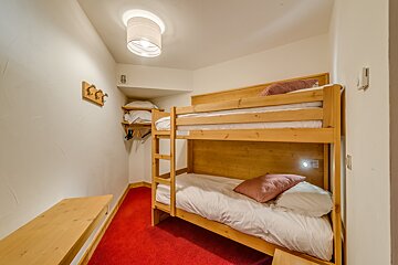 A bunk bed in a small room with a red carpet