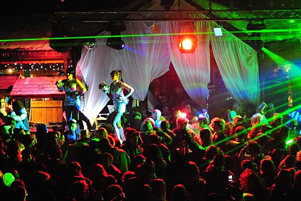 A group of people are dancing in a club with green lights