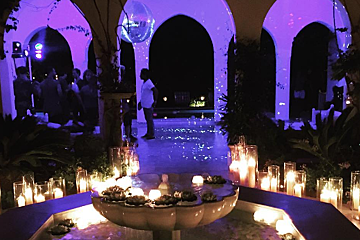 A fountain is lit up with purple lights and candles