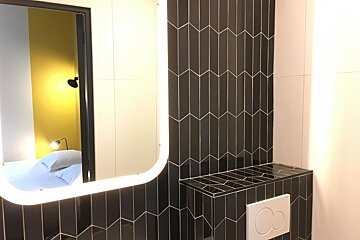 A bathroom with black and white tiles and a lighted mirror