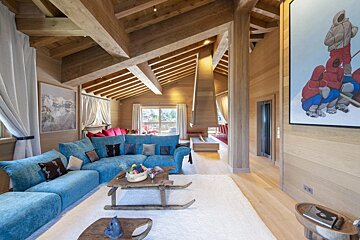 A living room with blue couches and a painting on the wall