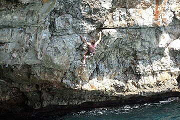 A climber free soloing above the sea in Mallorca