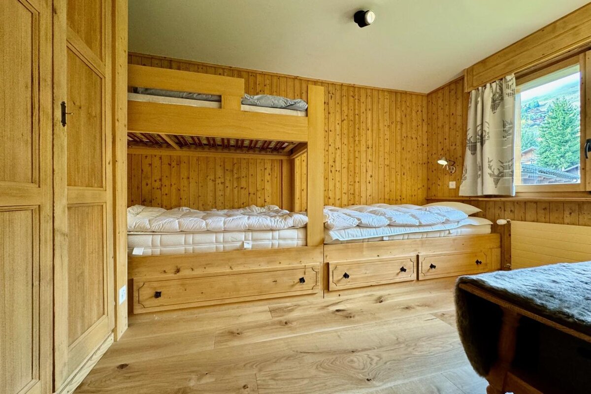 Two bunk beds in a wooden room with a window