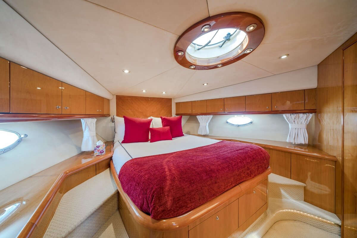 A bedroom on a boat with a red blanket and pillows