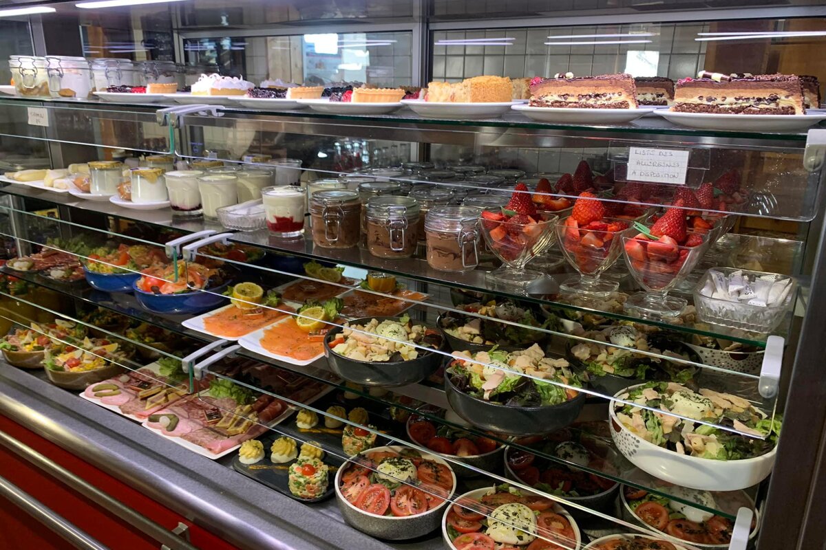 A display case filled with a variety of food including salads and desserts