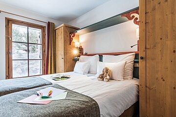 A bedroom with two beds and a teddy bear on the bed