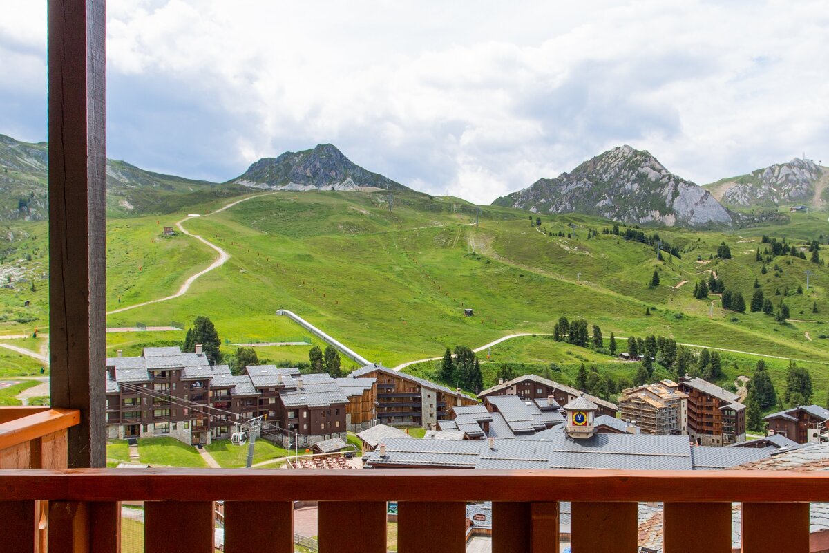 A balcony with a view of the mountains and buildings