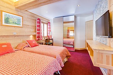 A bedroom with two beds and a flat screen tv