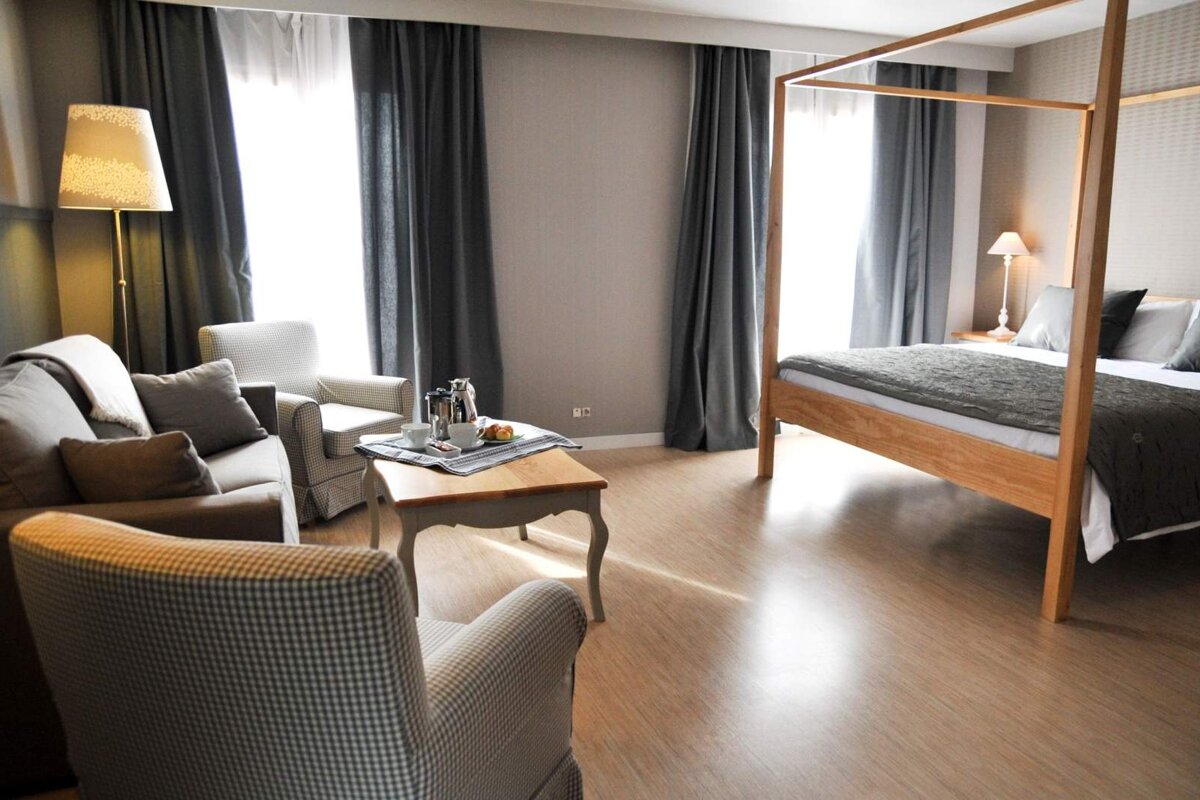 A hotel room with a four poster bed and a couch