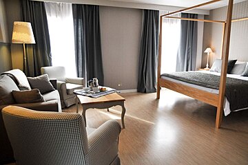 A hotel room with a four poster bed and a couch