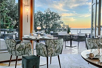 A restaurant with tables and chairs with a view of the ocean