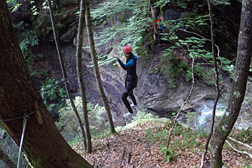 a person on a high wire across a river gully