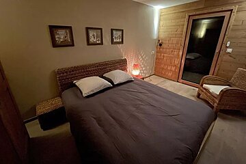 A bedroom with a wicker chair and a bed