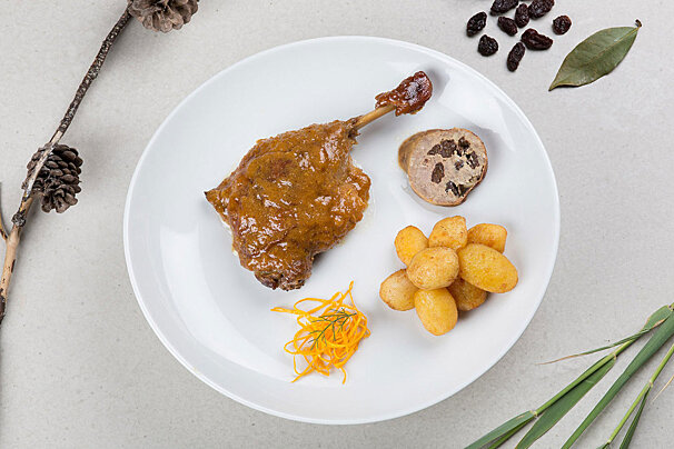 A white plate topped with meat potatoes and raisins