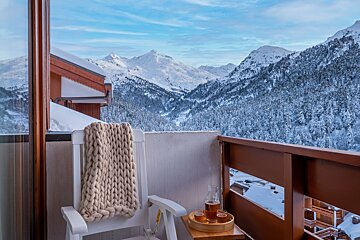 A balcony with a view of snowy mountains and trees