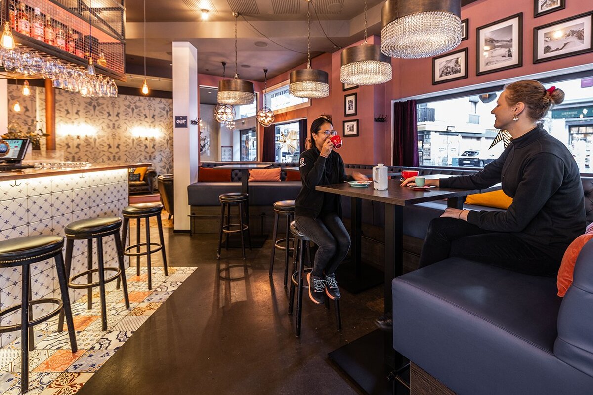 A woman sits at a table in a restaurant talking on a cell phone