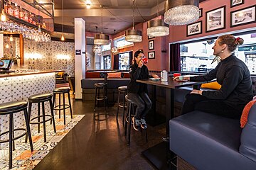 A woman sits at a table in a restaurant talking on a cell phone