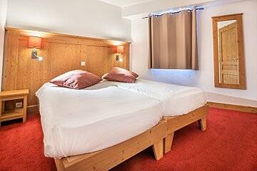 A bedroom with two beds and a mirror on the wall
