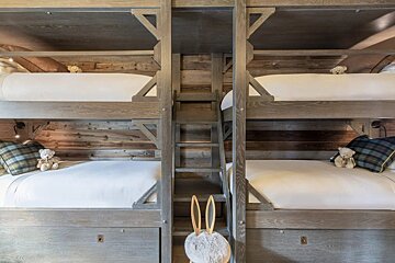 Three bunk beds with teddy bears on them in a room