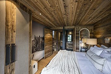 A bedroom with wooden walls and a large bed