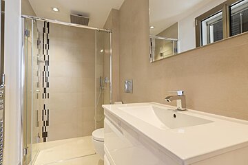 A bathroom with a walk in shower and a sink