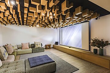A living room with a projector screen and a wooden ceiling