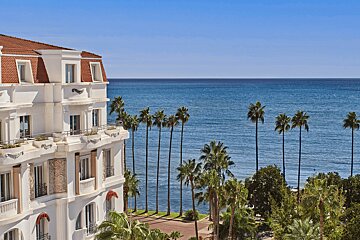 A large white building with a balcony overlooking the ocean