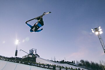A skier grabbing the tip of his ski mid flight