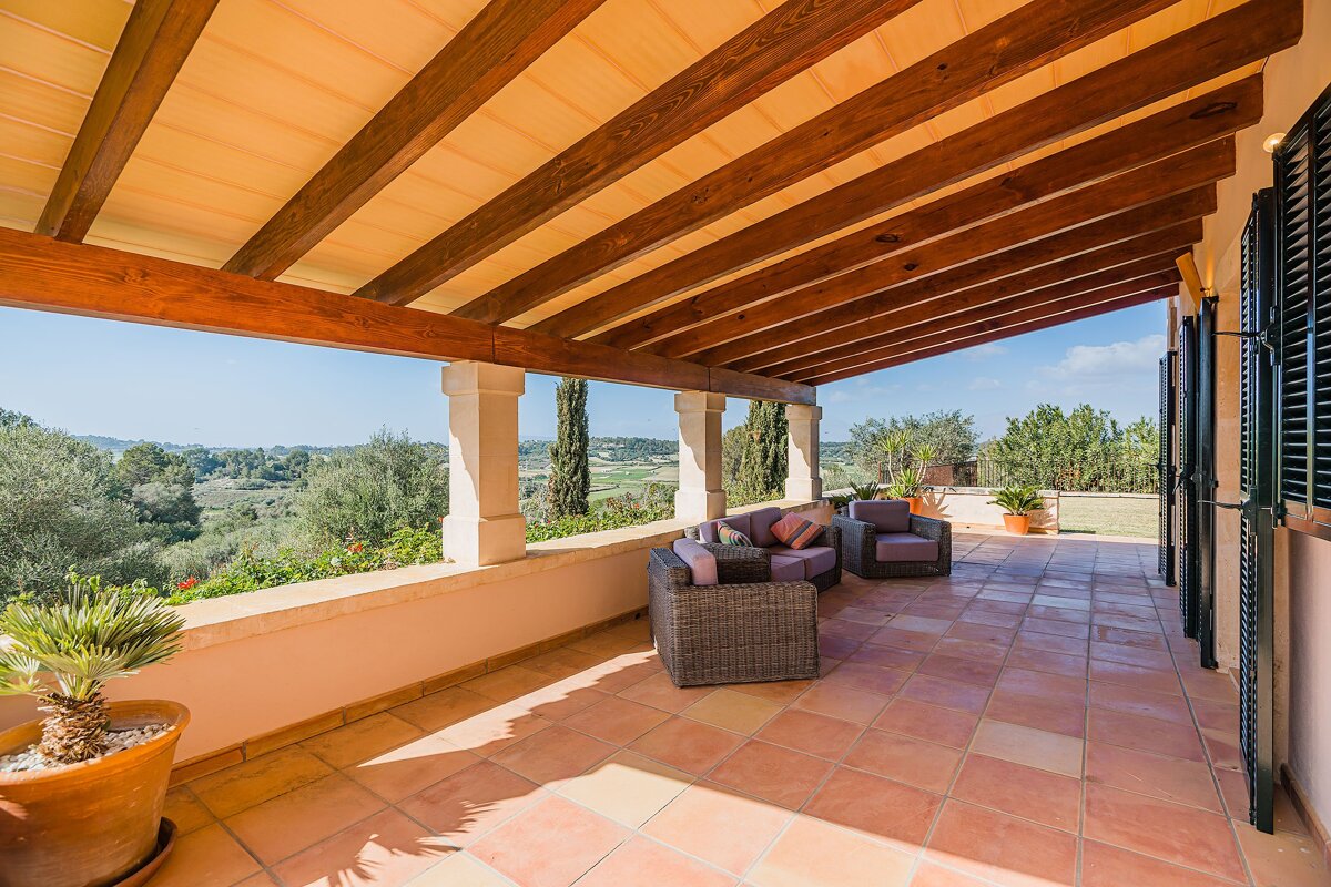 A balcony with a view of a lush green field