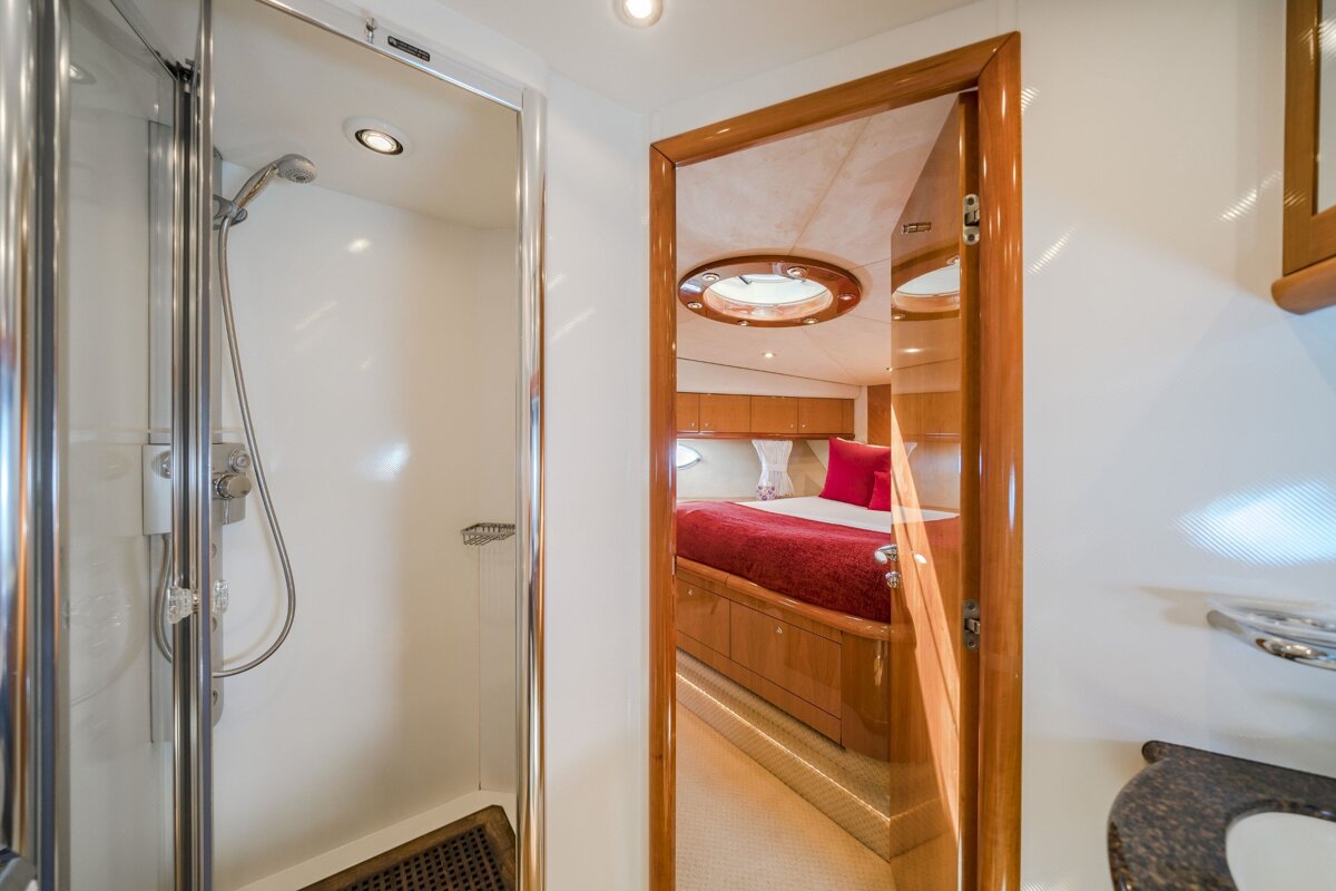 A bathroom with a shower and a bed in the background