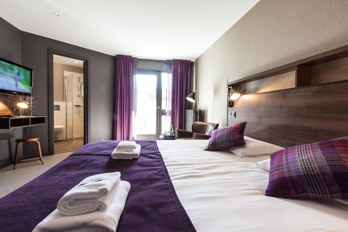 A hotel room with a bed and a chair