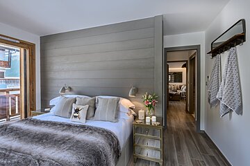 A bedroom with a bed and a mirrored nightstand